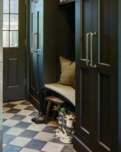 Limestone bench niche with open cubbies and tall inset cabinets—custom mudroom cabinets in Mendham, NJ by Wydian Kitchens.