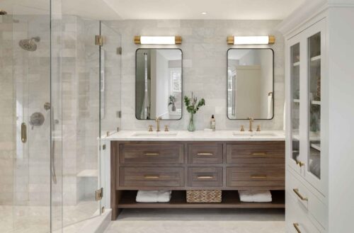 Wide view of an Exeter NH master bath remodel with custom walnut bathroom vanity, tall painted maple cabinet, and glass shower enclosure.