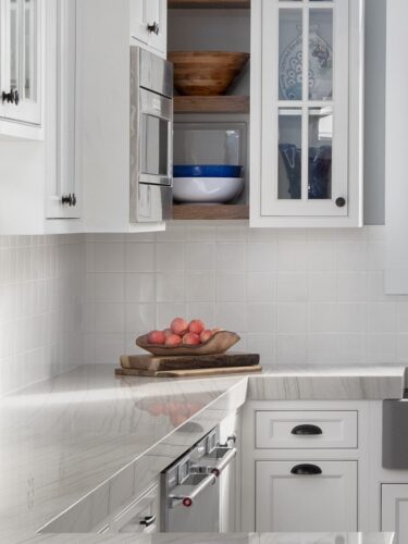 Custom white kitchen remodel Avalon NJ with Kountry Kraft cabinetry, hickory accents, and a wet bar designed for coastal living. Close up of white cabinetry, black cabinet hardware, white backsplash and countertops.
