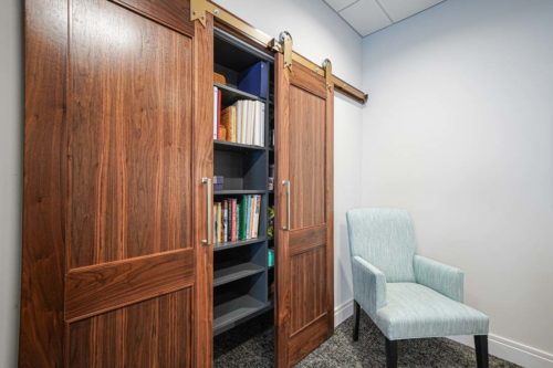 Walnut barn doors in executive office with custom cabinetry