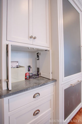 Cabinets with Hidden Outlets in Extra White Kitchen Cabinets Provides an Easily Accessible Place to Charge Electronics
