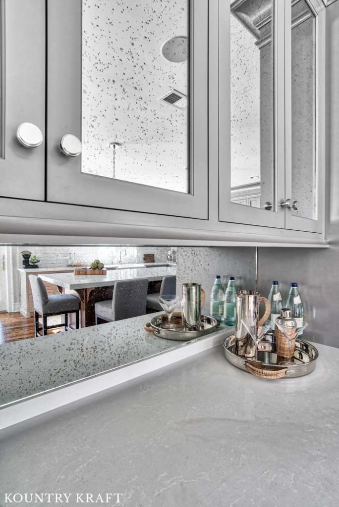 Dovetail Painted Cabinets with Antique Mirror Doors and Backsplash for a Wet Bar in a Transitional Kitchen with Wood Flooring