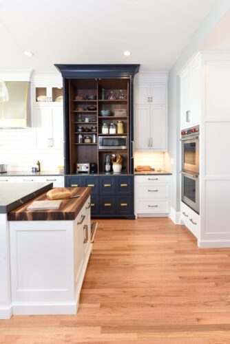 White and blue kitchen cabinets with a counter-to-ceiling appliance garage inspired by an armoire.