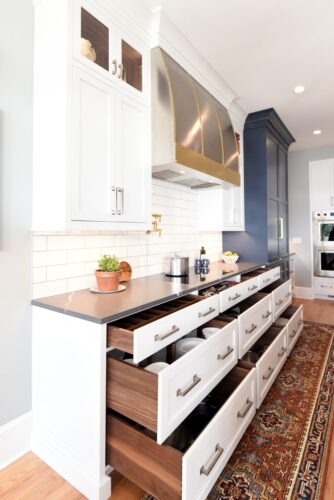 White an blue kitchen cabinets with walnut interior drawer boxes.