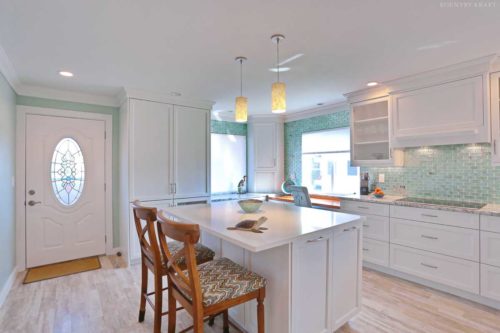This Kitchen Color Scheme Includes White Cabinetry with a Light Hardwood Floor and a Teal Backsplash
