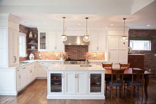 A custom range hood and alpine white custom cabinetry complete this kitchen focal point 