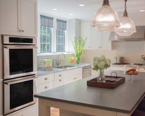 Light kitchen with house plants, two stacked ovens, and subway tile backsplash Merion Station, PA