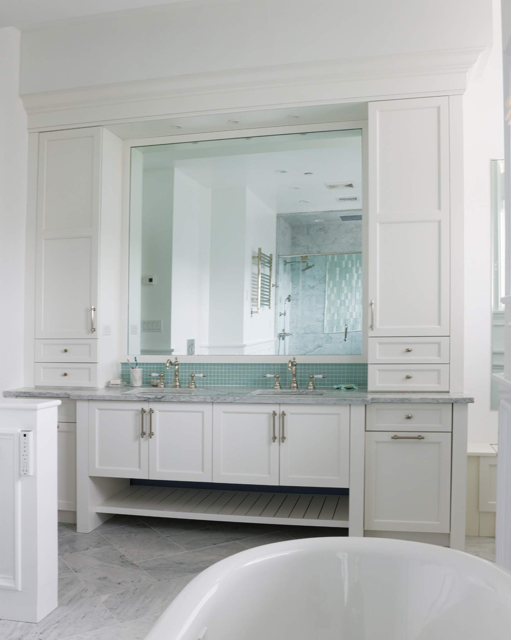 Custom cabinetry and full vanity wall with integrated mirror and marble counters in Point Lookout NY master bath.