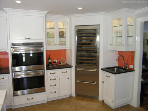 Modern kitchen cabinets with ovens, sink, wine cooler, and black countertops Darien, CT