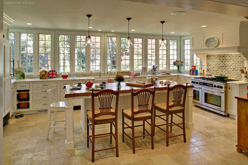 Zoom out of painted white cabinets, island with seating, range, and sink Summit, NJ