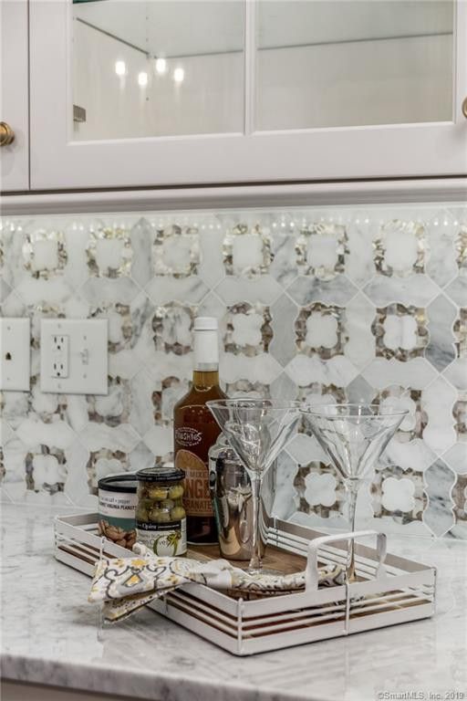 White Kitchen Cabinetry with Marble Counters and Backsplash