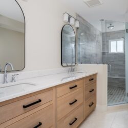 Double vanity with rift cut white oak cabinetry, quartz countertop, and arched mirrors in a Sea Isle City master bath remodel.