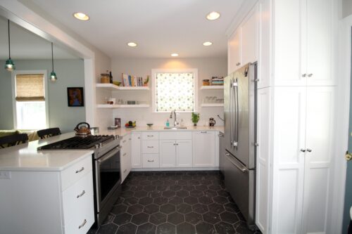Small kitchen cabinetry finished in a white paint. Open shelving. Black tile flooring.