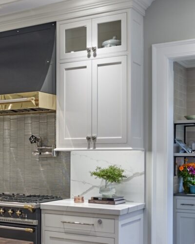 Custom Villanova kitchen with White Dove inset cabinetry, black-and-brass range, veined stone backsplash, and decorative countertop display.