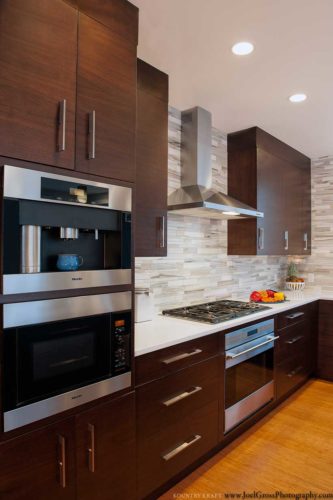 Walnut cabinetry, coffee machine, microwave, range, and L-shaped counter Swampscott, MA