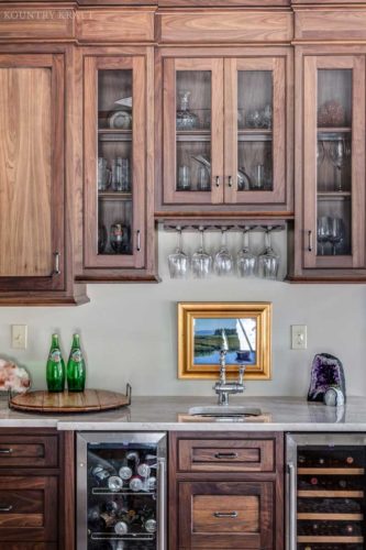 Walnut wet bar with wine coolers, glass panel cabinet doors, and stemware racks Madison, NJ