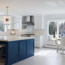 Wide view of a white and blue kitchen remodel in Brookville NY with custom cabinetry and marble island.