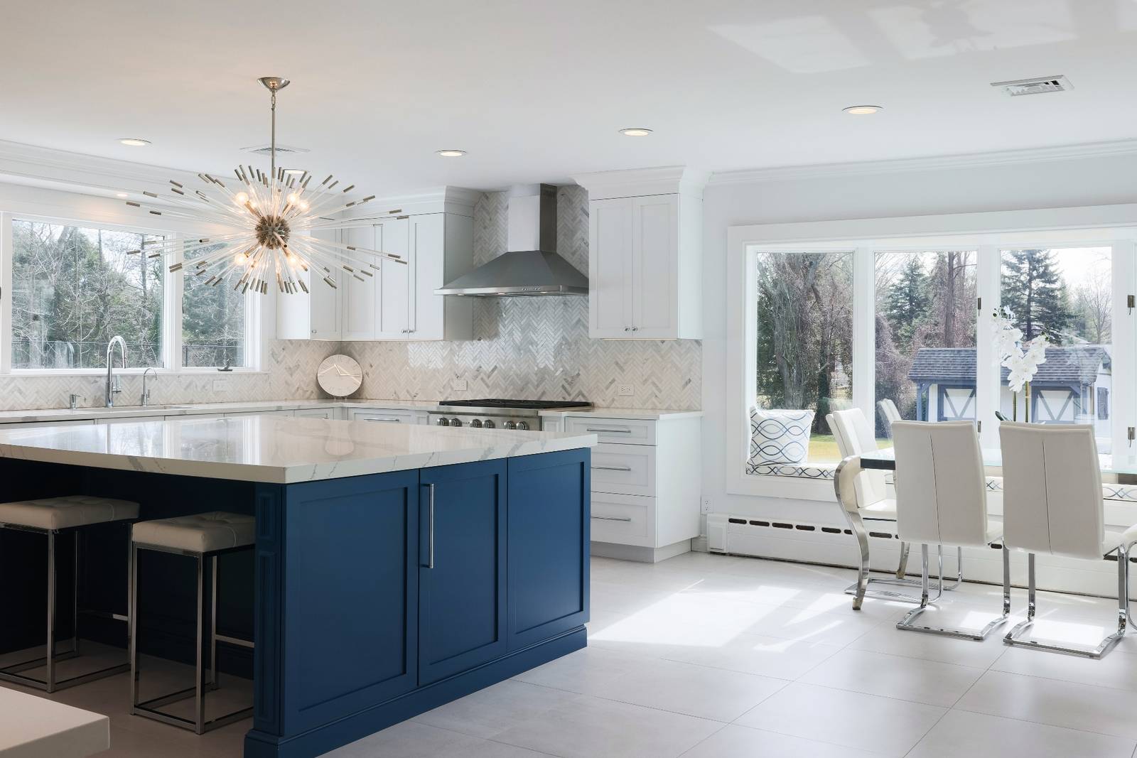 Wide view of a white and blue kitchen remodel in Brookville NY with custom cabinetry and marble island.
