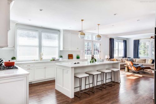 View of white kitchen showing an island with four stools, countertops, and cabinets Short Hills, NJ