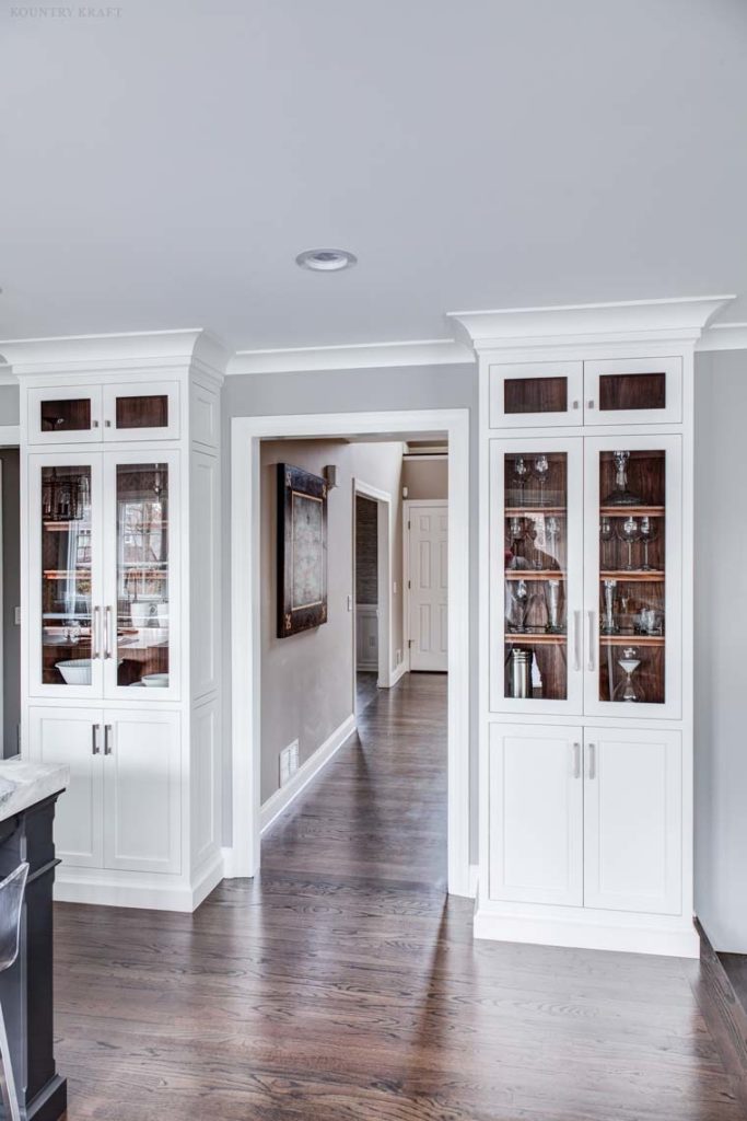 Custom White cabinetry with glass doors and walnut wood shelves in New Jersey