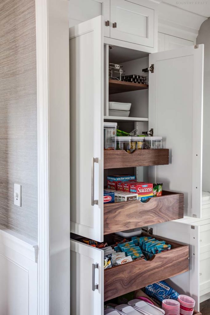 Pantry made of white cabinetry with pull out walnut wood drawers in New Jersey